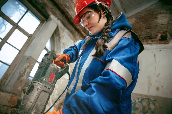 Mujer usando casco usando herramientas de trabajo masculinas — Foto de Stock