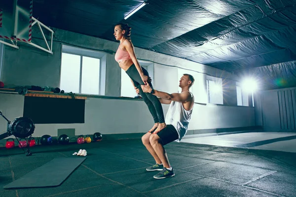 Tiro de hombre joven y una mujer de pie en posición de tabla en el gimnasio — Foto de Stock