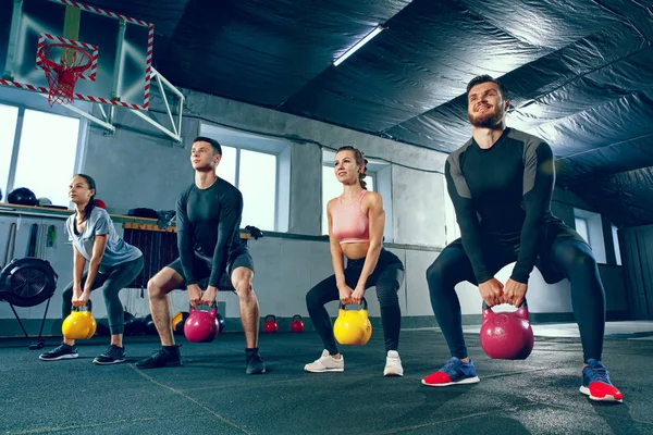 Die starken jungen Fitness-Männer und -Frauen in Sportbekleidung bei Übungen im Fitnessstudio — Stockfoto