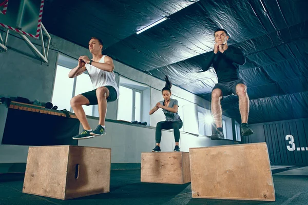Grupo de deportistas musculosos están haciendo ejercicio en el gimnasio . — Foto de Stock