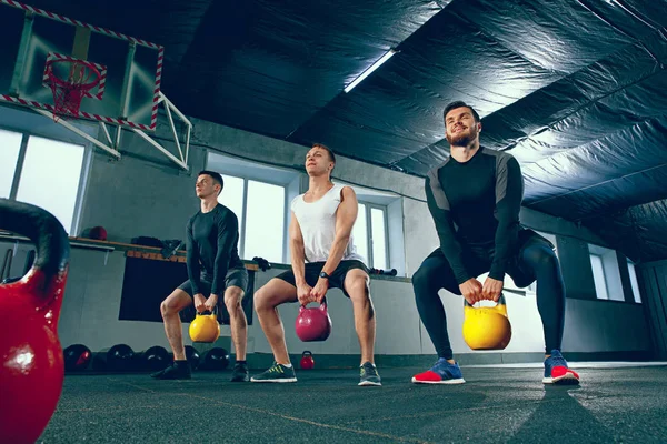 Die starken jungen Fitness-Männer in Sportbekleidung bei Übungen im Fitnessstudio — Stockfoto