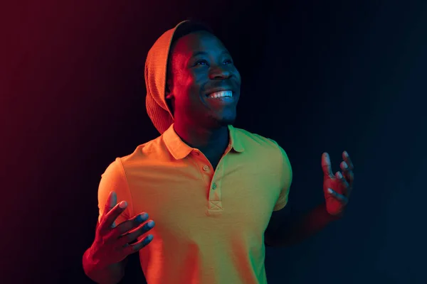 Retrato de um jovem afro-americano feliz sorrindo em fundo de néon preto — Fotografia de Stock