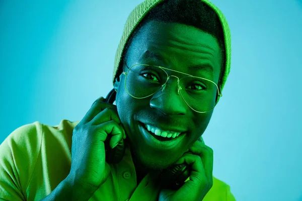 Портрет щасливого молодого афроамериканця, який посміхається на чорному неоновому тлі — стокове фото
