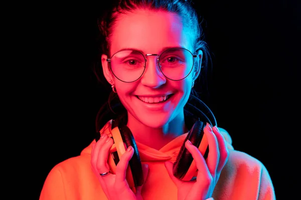Мода красива жінка з навушниками, що слухають музику на неоновому фоні — стокове фото