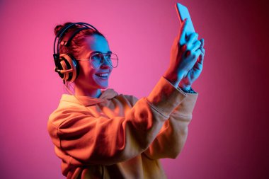 Neon arka plan üzerinde müzik kulaklık ile güzel kadın moda