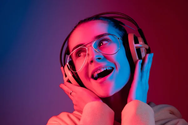 ネオンの背景に音楽を聴くヘッドフォンでファッション プリティウーマン — ストック写真