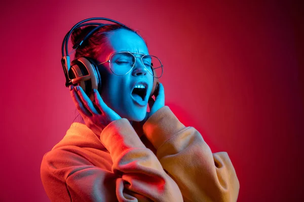 Mode hübsche Frau mit Kopfhörern Musik über Neon-Hintergrund hören — Stockfoto