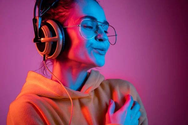 Moda bella donna con le cuffie ascoltare musica su sfondo neon — Foto Stock