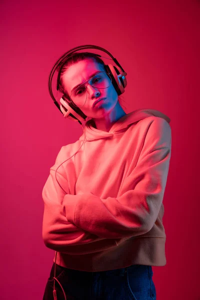 De mooie vrouw mode met koptelefoon luisteren naar muziek via neon achtergrond — Stockfoto