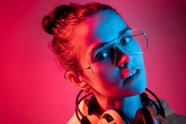 De mooie vrouw mode met koptelefoon luisteren naar muziek via neon achtergrond — Stockfoto