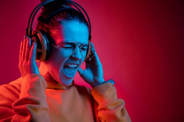 Moda bella donna con le cuffie ascoltare musica su sfondo neon — Foto Stock