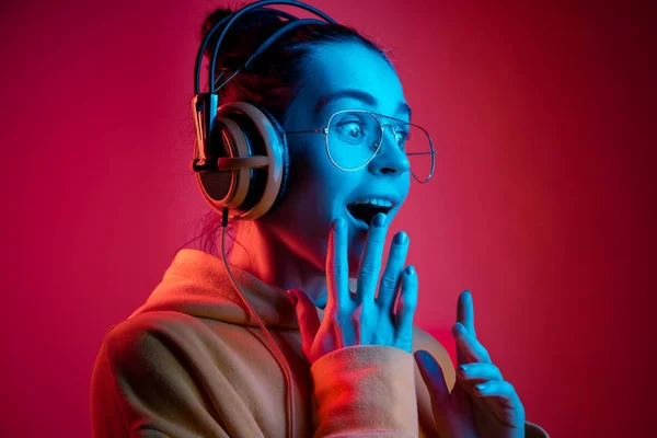 Fashion wanita cantik dengan headphone mendengarkan musik di atas neon latar belakang — Stok Foto