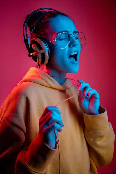 Moda mujer bonita con auriculares escuchando música sobre fondo de neón — Foto de Stock