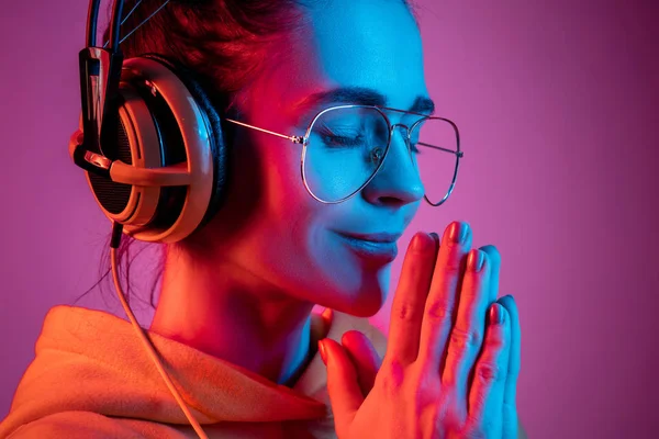 Moda bella donna con le cuffie ascoltare musica su sfondo neon — Foto Stock