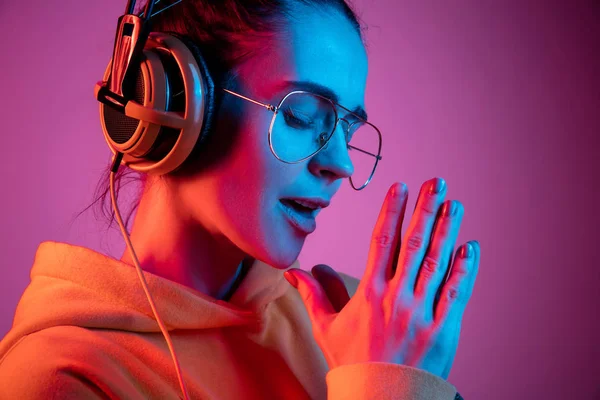 Moda bella donna con le cuffie ascoltare musica su sfondo neon — Foto Stock