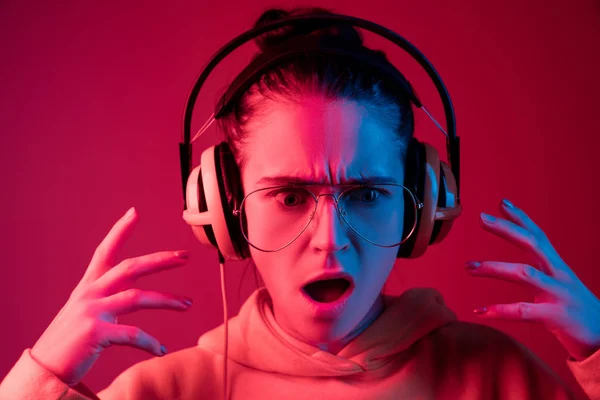 Moda mujer bonita con auriculares escuchando música sobre fondo de neón — Foto de Stock