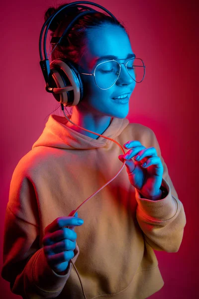 Moda mulher bonita com fones de ouvido ouvir música sobre fundo de néon — Fotografia de Stock