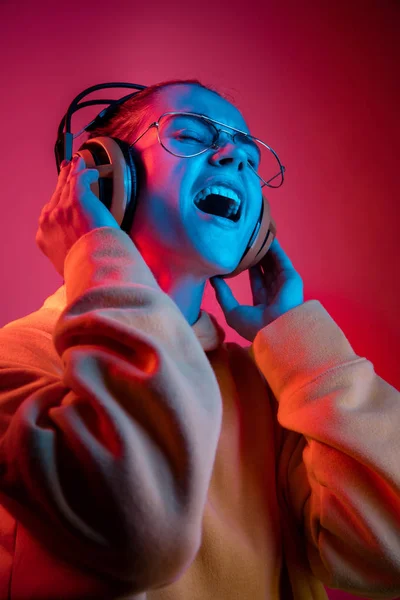 Ładna kobieta moda z słuchawki, słuchanie muzyki na tle neon — Zdjęcie stockowe