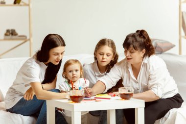Küçük kız, çekici genç anne ve büyüleyici büyükanne evde oturuyor