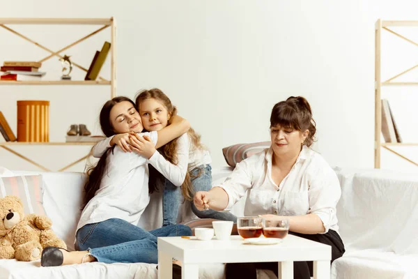 Kislányok, vonzó fiatal anya és bájos nagymamája ül otthon — Stock Fotó