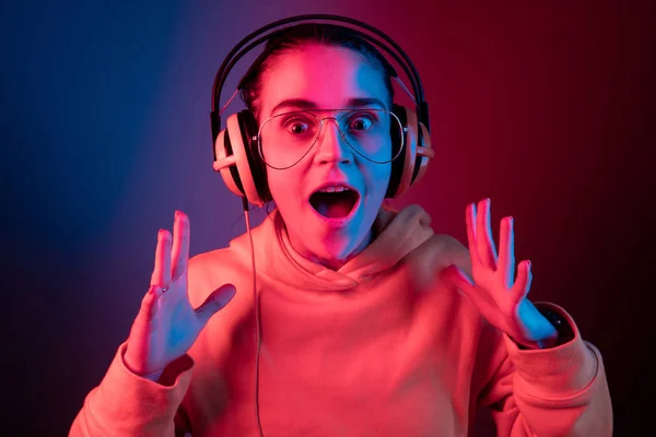 Módní pretty woman s sluchátka, poslech hudby přes neon pozadí — Stock fotografie