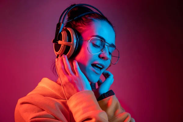 Moda bella donna con le cuffie ascoltare musica su sfondo neon — Foto Stock