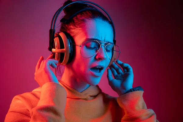 Moda mulher bonita com fones de ouvido ouvir música sobre fundo de néon — Fotografia de Stock