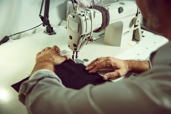 Sewing process of the leather belt. old Mans hands behind sewing.