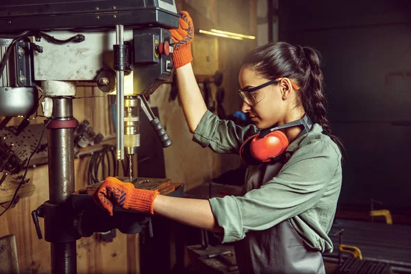 Busy and serious craftswoman grinding timbers with special machine. — Stock Photo, Image