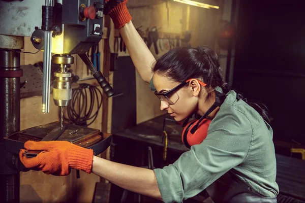 Busy and serious craftswoman grinding timbers with special machine. — Stock Photo, Image