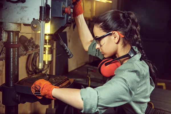 Busy and serious craftswoman grinding timbers with special machine. — Stock Photo, Image