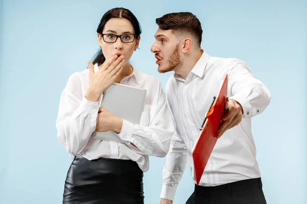 El hombre y la mujer de negocios sorprendidos sonriendo sobre un fondo gris — Foto de Stock