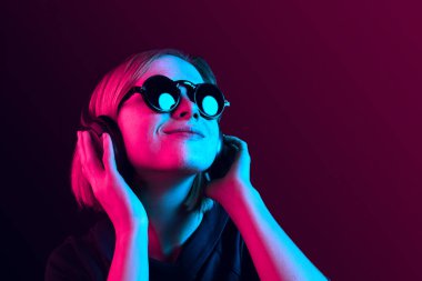 Neon arka plan üzerinde müzik kulaklık ile güzel kadın moda