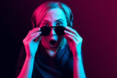 Neon arka plan üzerinde müzik kulaklık ile güzel kadın moda