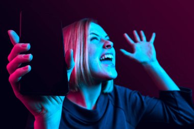 Boş ekran cep telefonu izole mavi arka plan üzerinde gösterilen kendine güvenen bir casual kız portresi