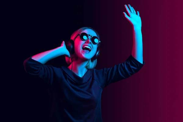 Moda mujer bonita con auriculares escuchando música sobre fondo de neón — Foto de Stock