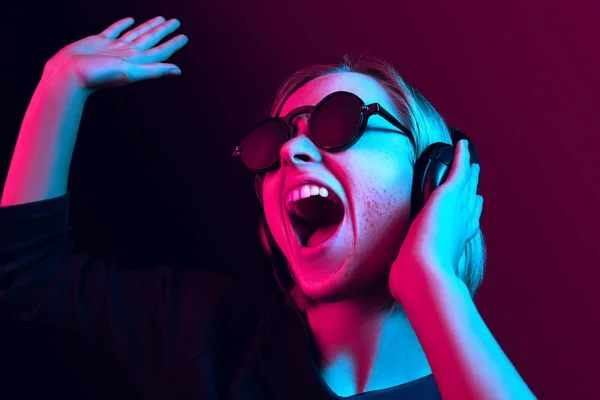 Ładna kobieta moda z słuchawki, słuchanie muzyki na tle neon — Zdjęcie stockowe
