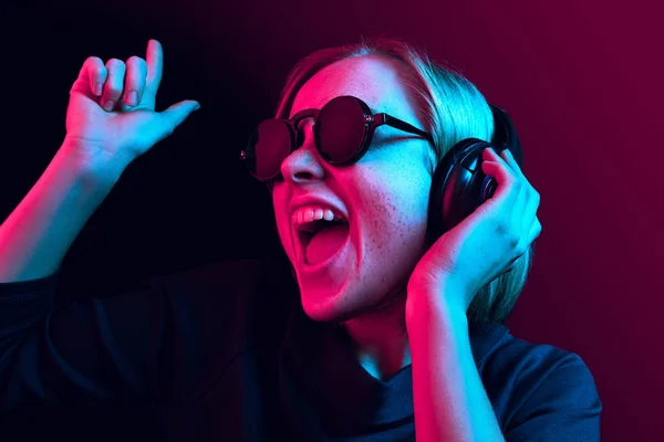 Moda mujer bonita con auriculares escuchando música sobre fondo de neón — Foto de Stock