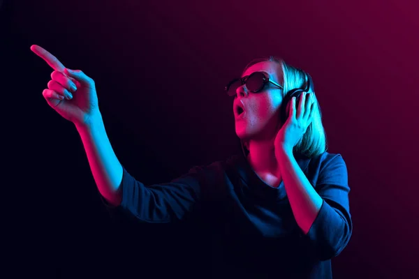 Módní pretty woman s sluchátka, poslech hudby přes neon pozadí — Stock fotografie