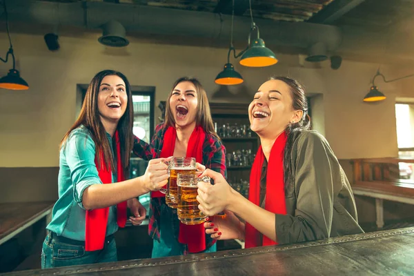 Deporte, gente, ocio, amistad y entretenimiento: aficionados al fútbol felices o amigas bebiendo cerveza y celebrando la victoria en el bar o pub — Foto de Stock