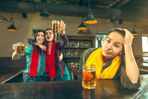 Sport, people, leisure, friendship and entertainment concept - happy football fans or female friends drinking beer and celebrating victory at bar or pub