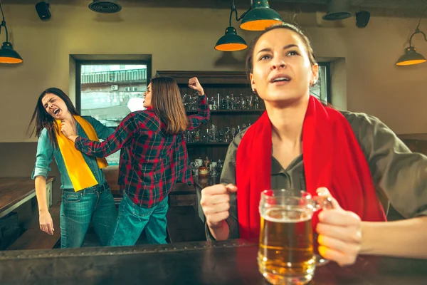 Deporte, gente, ocio, amistad y entretenimiento: aficionados al fútbol felices o amigas bebiendo cerveza y celebrando la victoria en el bar o pub — Foto de Stock