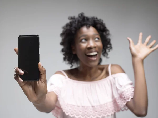 Retrato de una chica afro casual confiada que muestra el teléfono móvil de pantalla en blanco —  Fotos de Stock