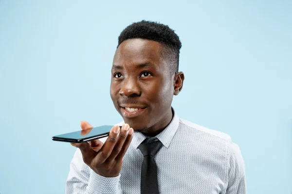 Retrato interior de atractivo joven negro sosteniendo teléfono inteligente en blanco — Foto de Stock