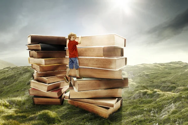 Mały chłopiec, wspinaczka na wieżę z duże książki — Zdjęcie stockowe