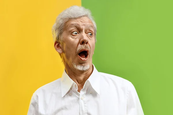 El hombre mayor mirando sorprendido aislado en el fondo del estudio de color — Foto de Stock