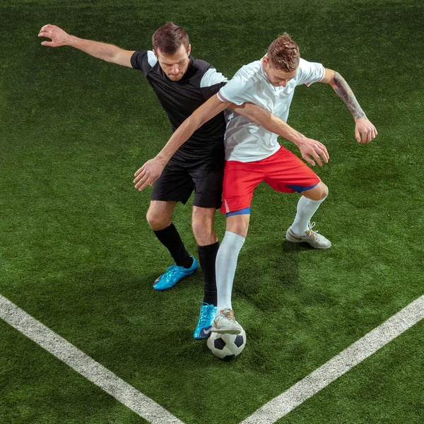 Football players tackling ball over green grass background — Stock Photo, Image