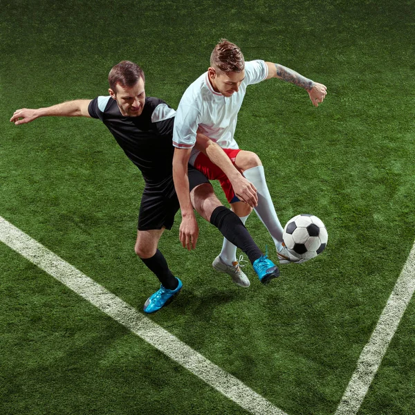 Football players tackling ball over green grass background