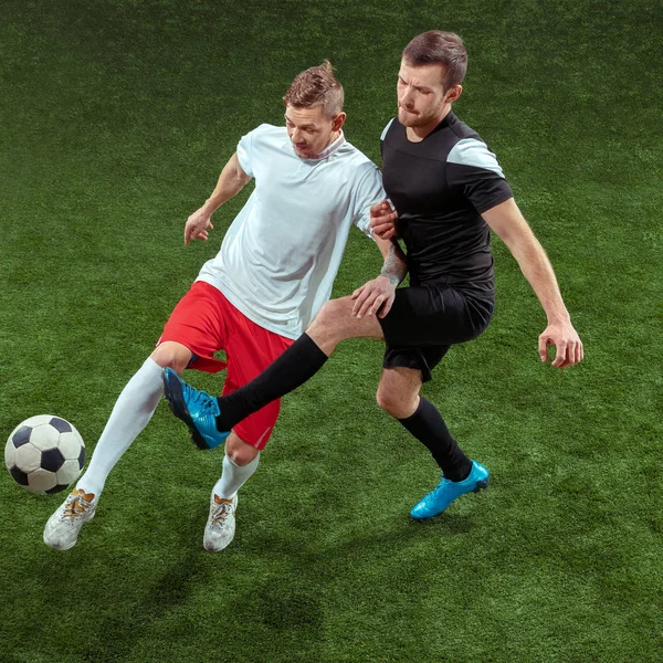 Football players tackling ball over green grass background — Stock Photo, Image