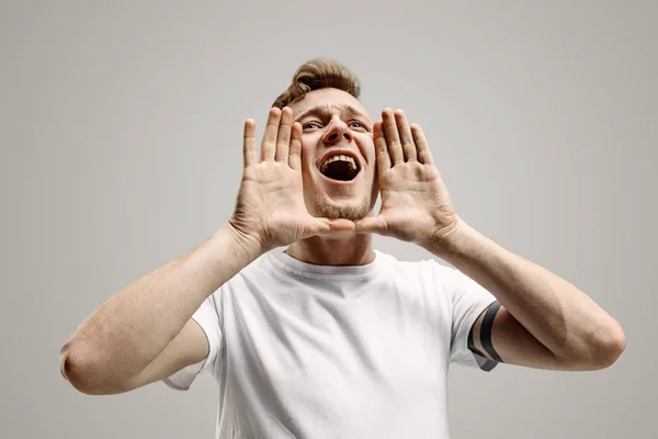 Geïsoleerd op grijze casual jongeman schreeuwen in studio — Stockfoto